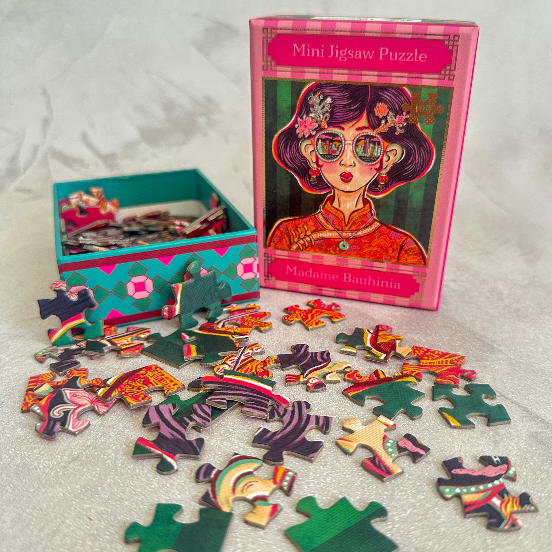 Mini jigsaw puzzle set with colorful pieces and a box featuring a stylized illustration of a woman.