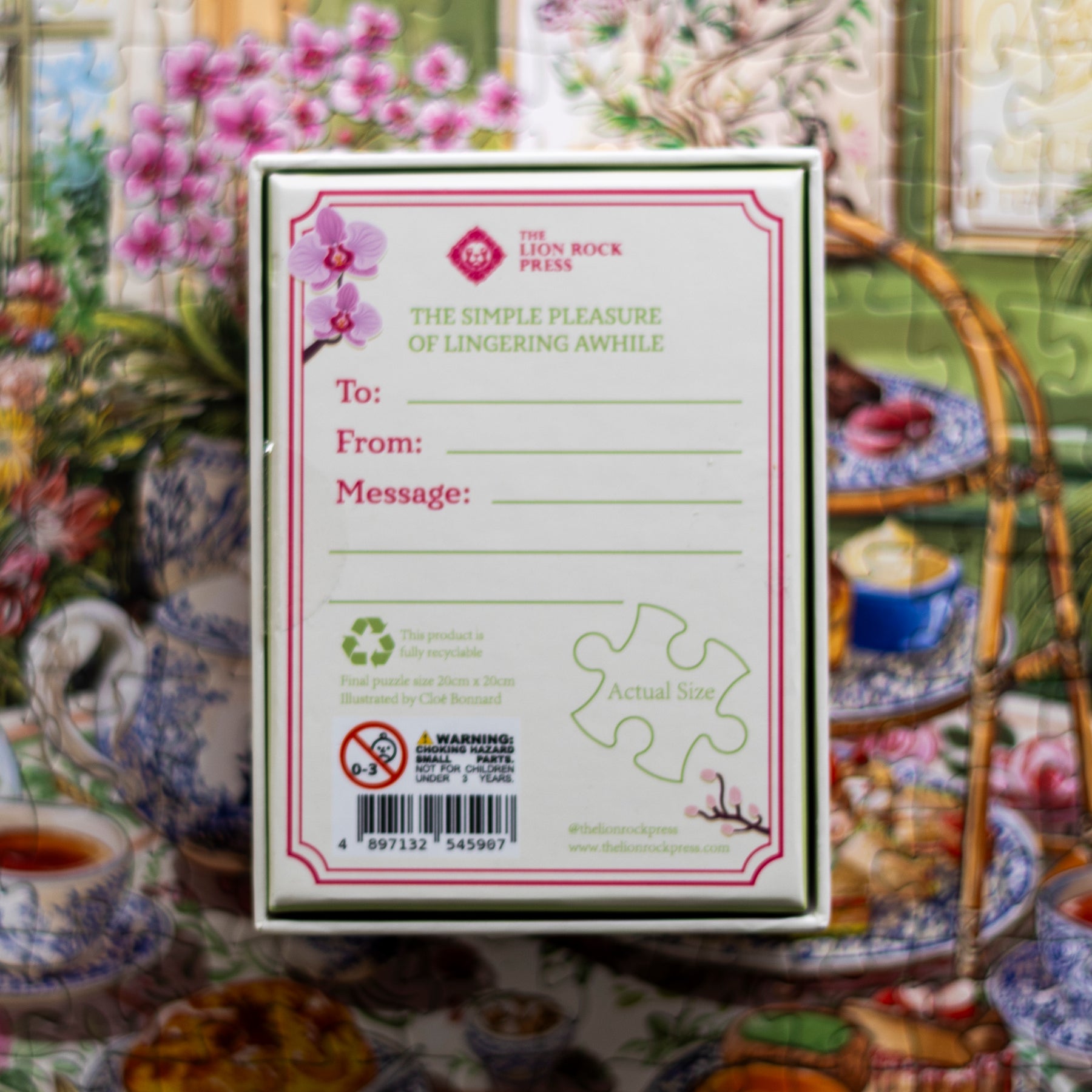 The back of a white carded box from The Leon Rock Press, featuring a pink orchid illustration and printed text, set against a colorful, busy floral background.