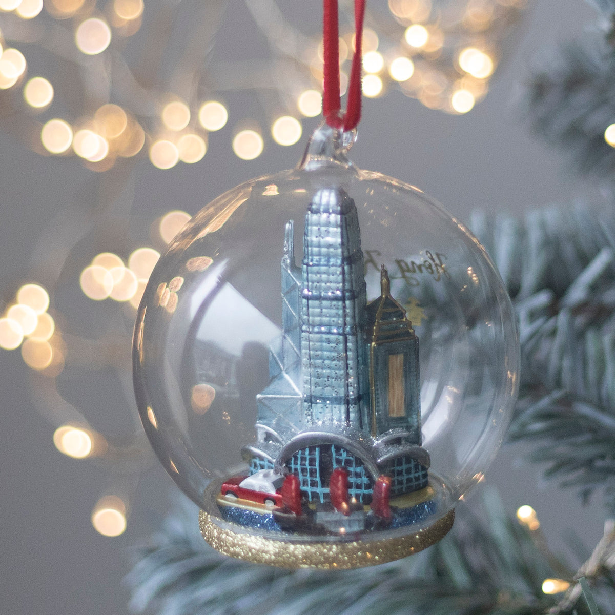 Glass Christmas ornament with a Hong Kong cityscape inside, hanging on a tree 