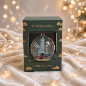 Glass Christmas ornament with a Hong Kong cityscape inside, green and luxe gold foiled packaging.